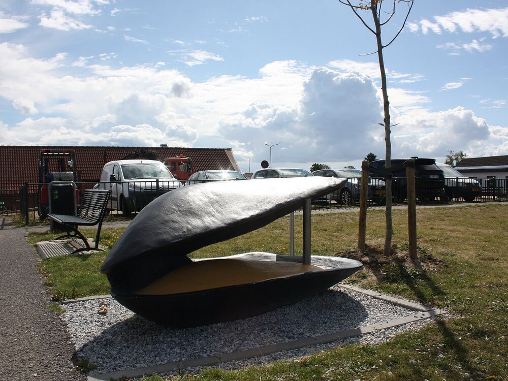 Een groot kunstwerk in de vorm van een opengaande mosselschelp in het gras in Yerseke
